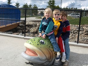 Children playing on steelhead trout in accessible splash pad