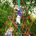 children climb net web at inclusive playground